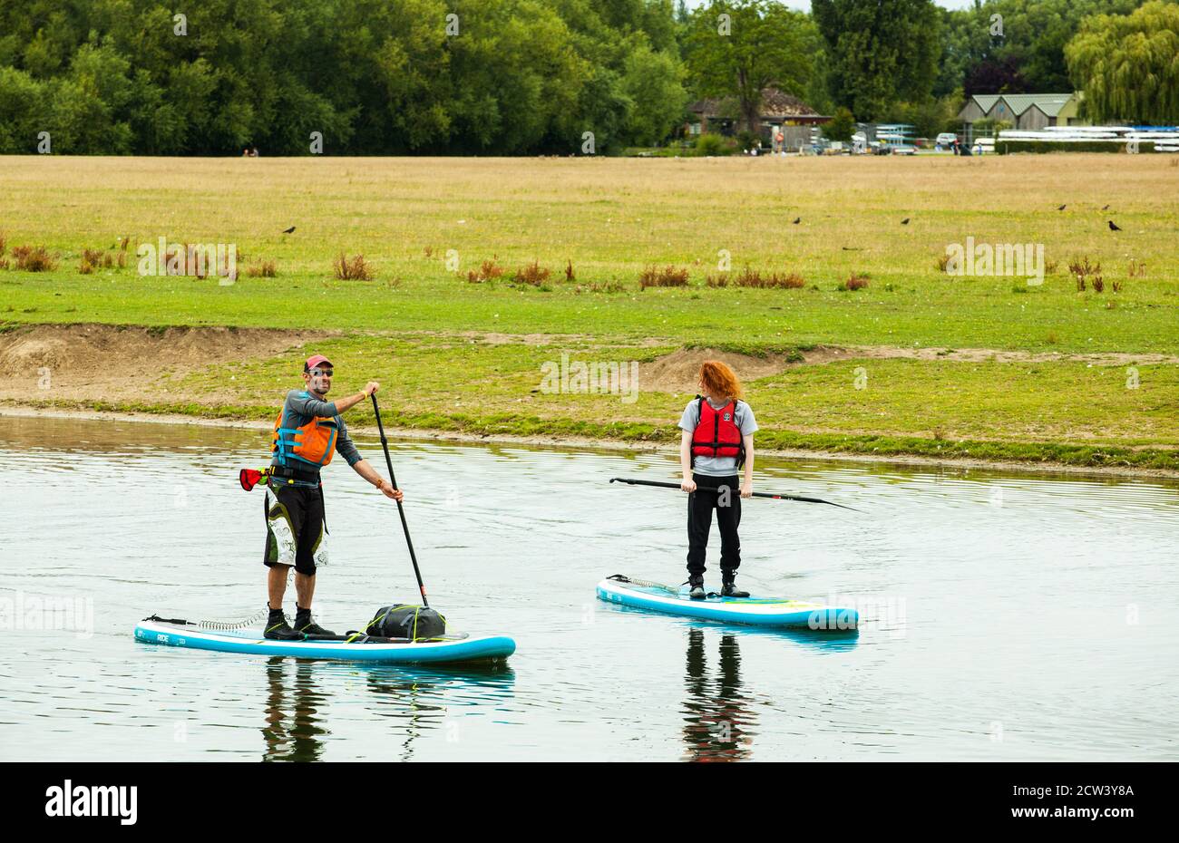 Due persone si levano in piedi su paddle boarding sul fiume Tamigi Oxfordshire Inghilterra Regno Unito Foto Stock
