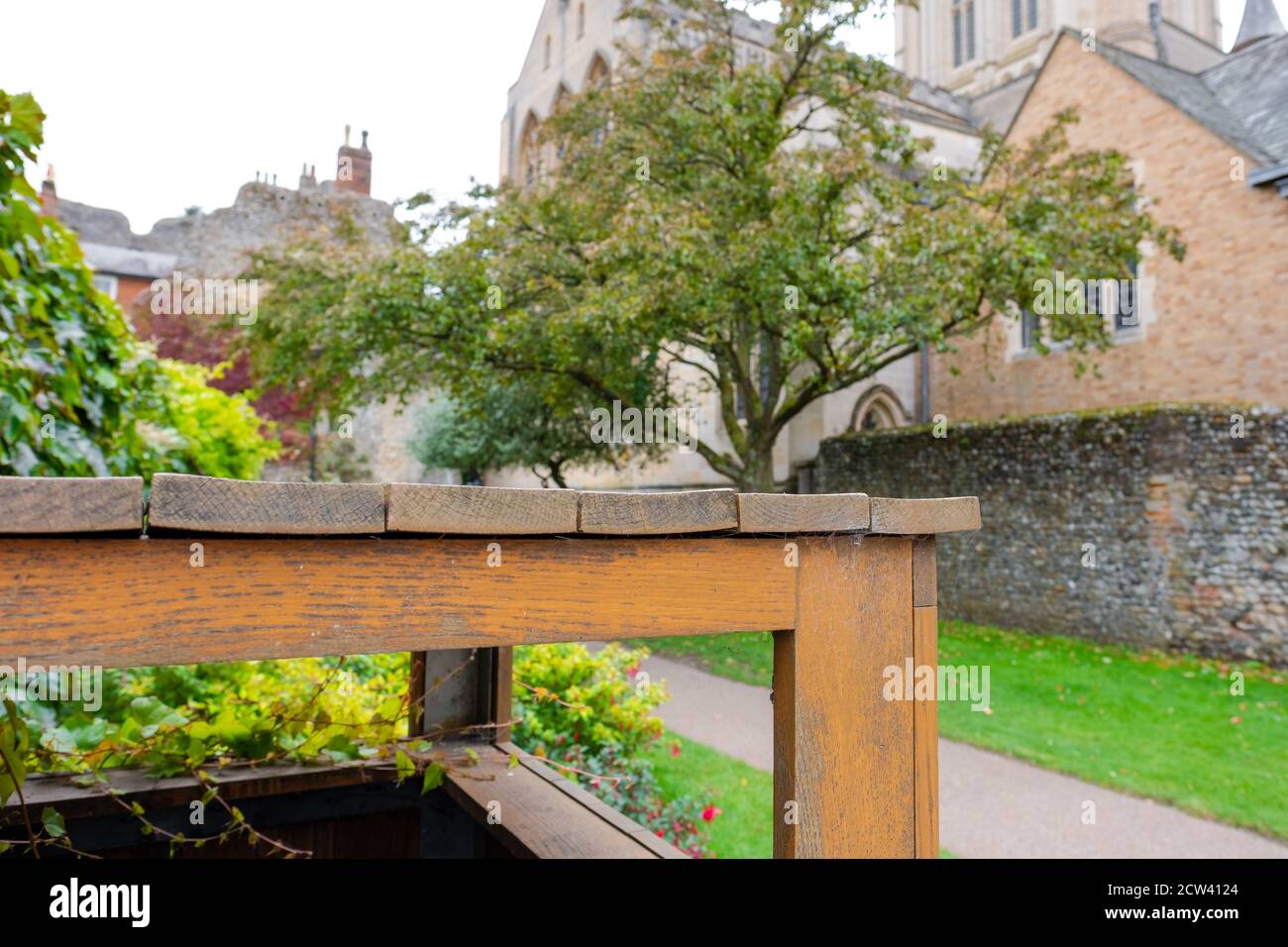 Fuoco basso di un bidone di lettiera di legno visto vicino al confine di un'antica parete di selce nelle vicinanze e la Cattedrale inglese. Foto Stock