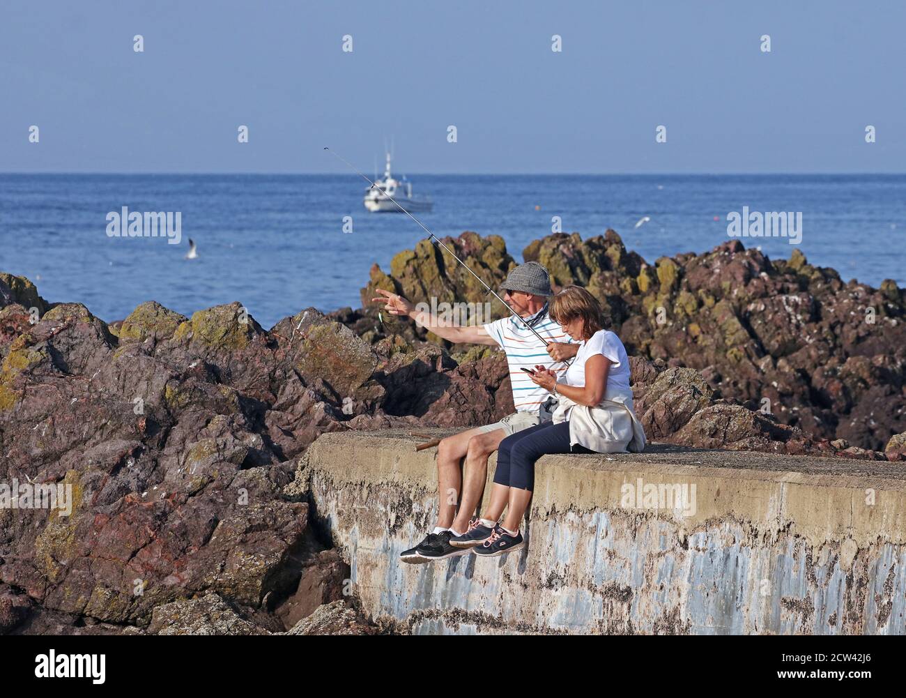 Uomo pesca con partner a St Abbs. Scozia Foto Stock
