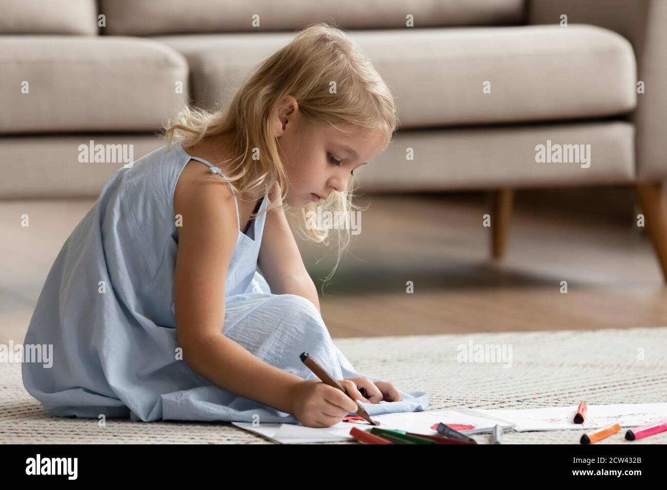 Ispirata ragazza prescolare seduta su pavimento caldo disegnando mondo immaginario Foto Stock