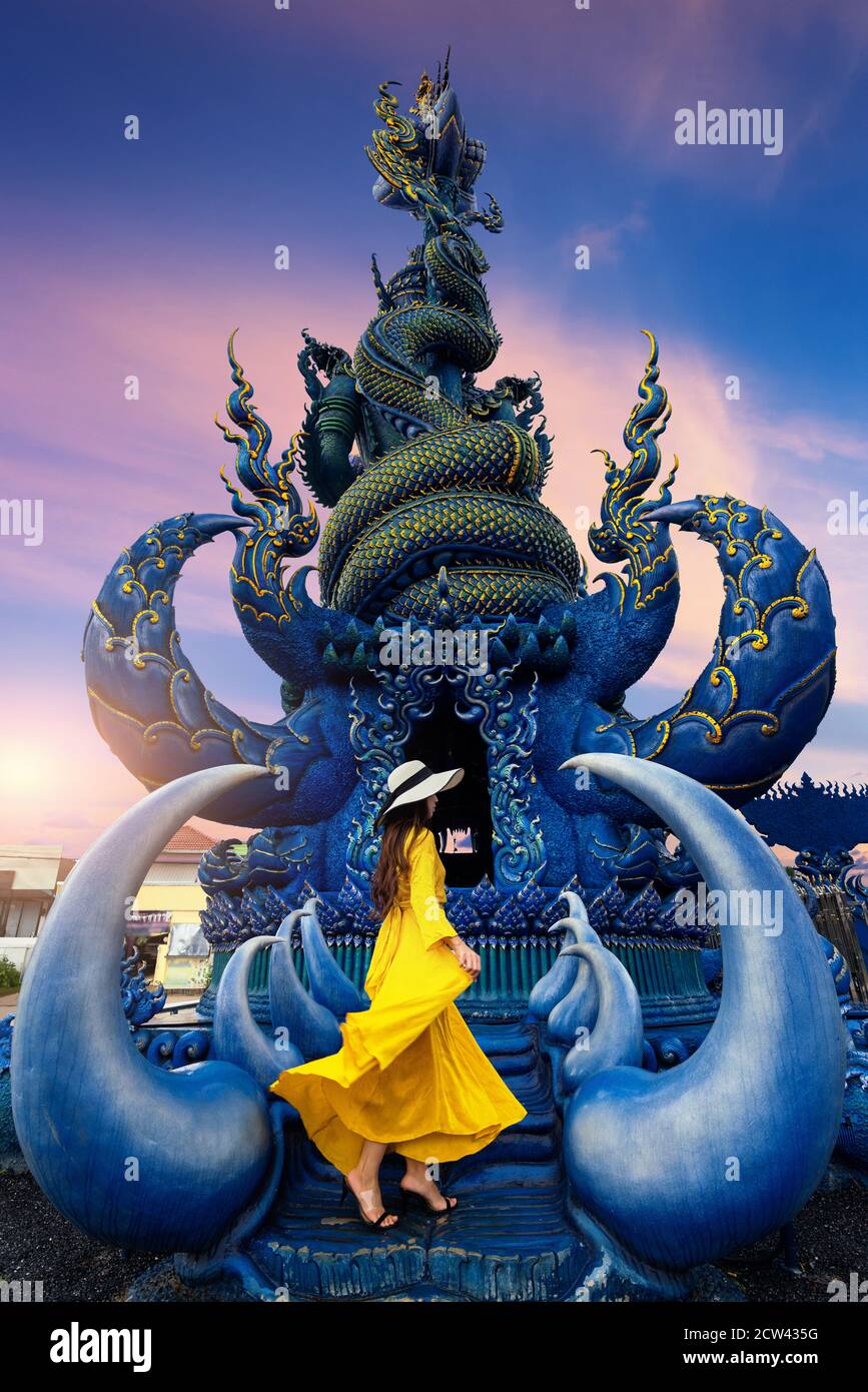 Donna che indossa un abito giallo a Wat rong suea dieci o tempio blu a Chiang rai, Thailandia. Foto Stock