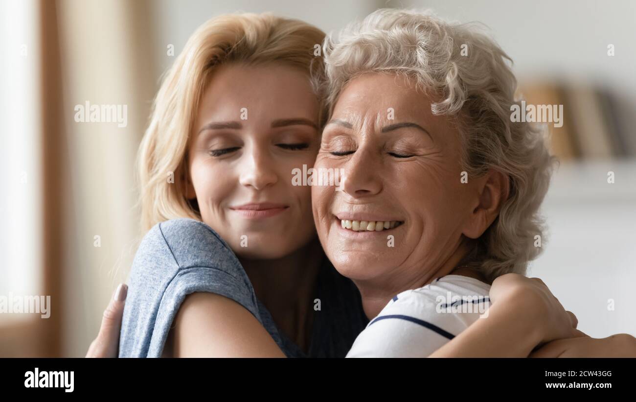 Madre anziana e figlia cresciuta coccolarsi con amore e affetto Foto Stock