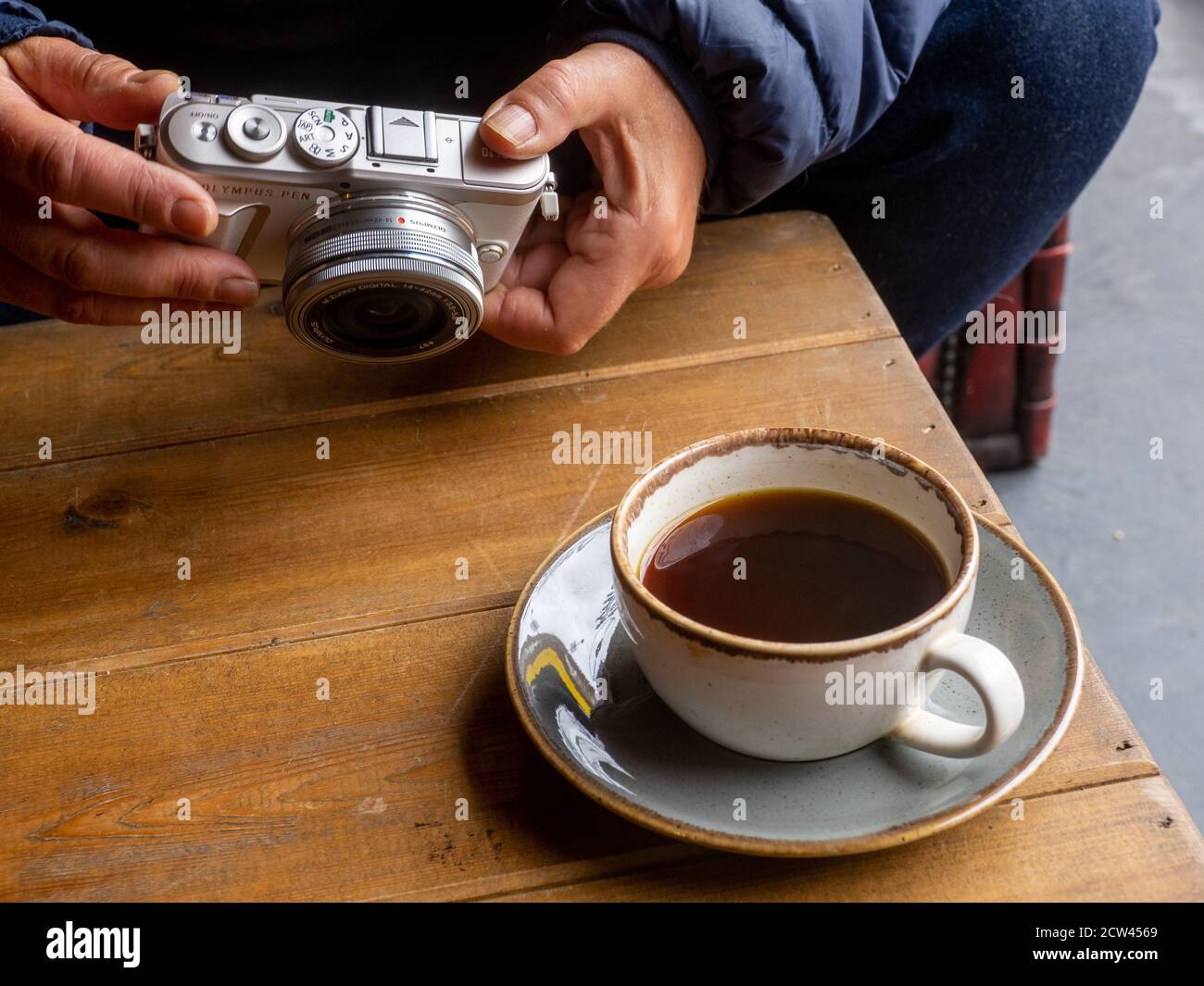 Una tazza di caffè nero e una macchina fotografica su un tavolo. Foto Stock