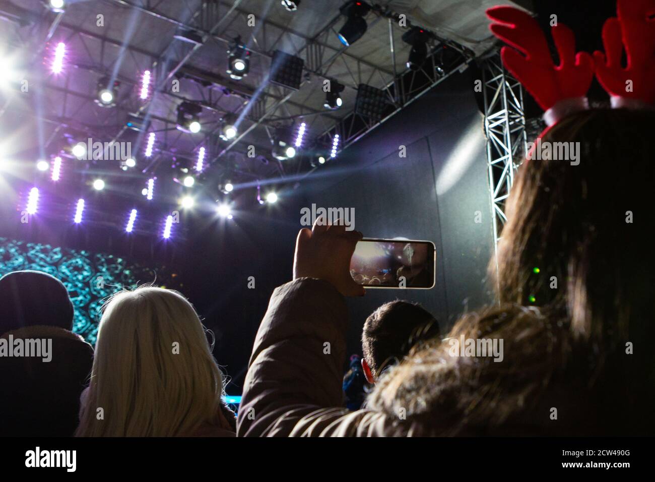 Una ragazza sta scattando le foto di un concerto di strada sopra il telefono Foto Stock