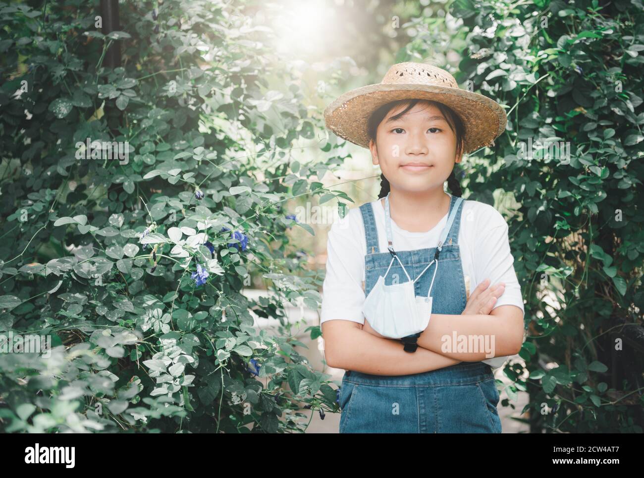 Ragazza contadina che indossa tute in denim con cappello e appende una  maschera nel giardino di verdure Foto stock - Alamy