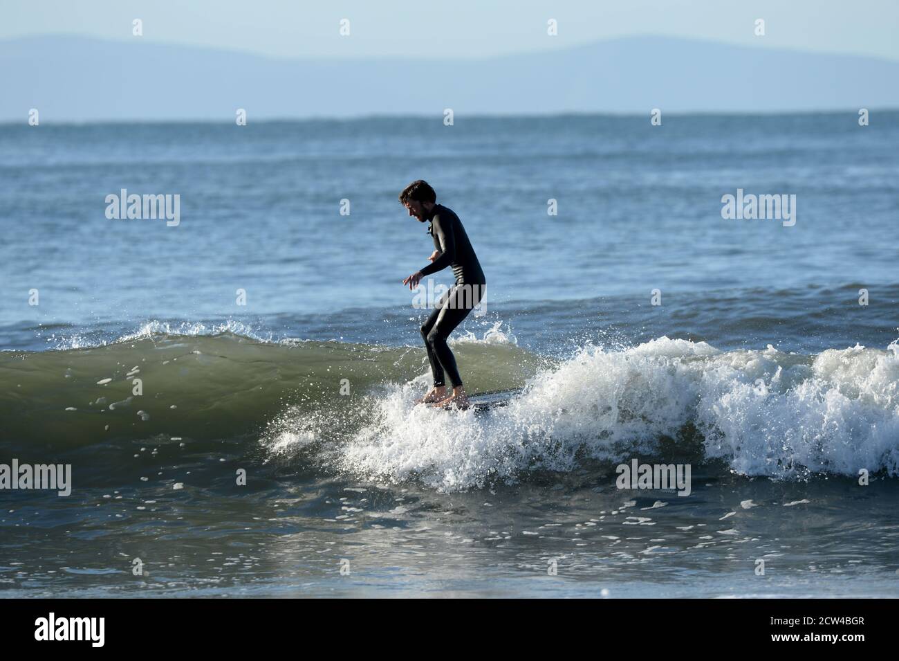 Surfer esegue Hang Ten su longboard. Con tutte le dita del piede sul naso, questa manovra sulla sezione veloce dell'onda massimizza l'energia potenziale della guida Foto Stock