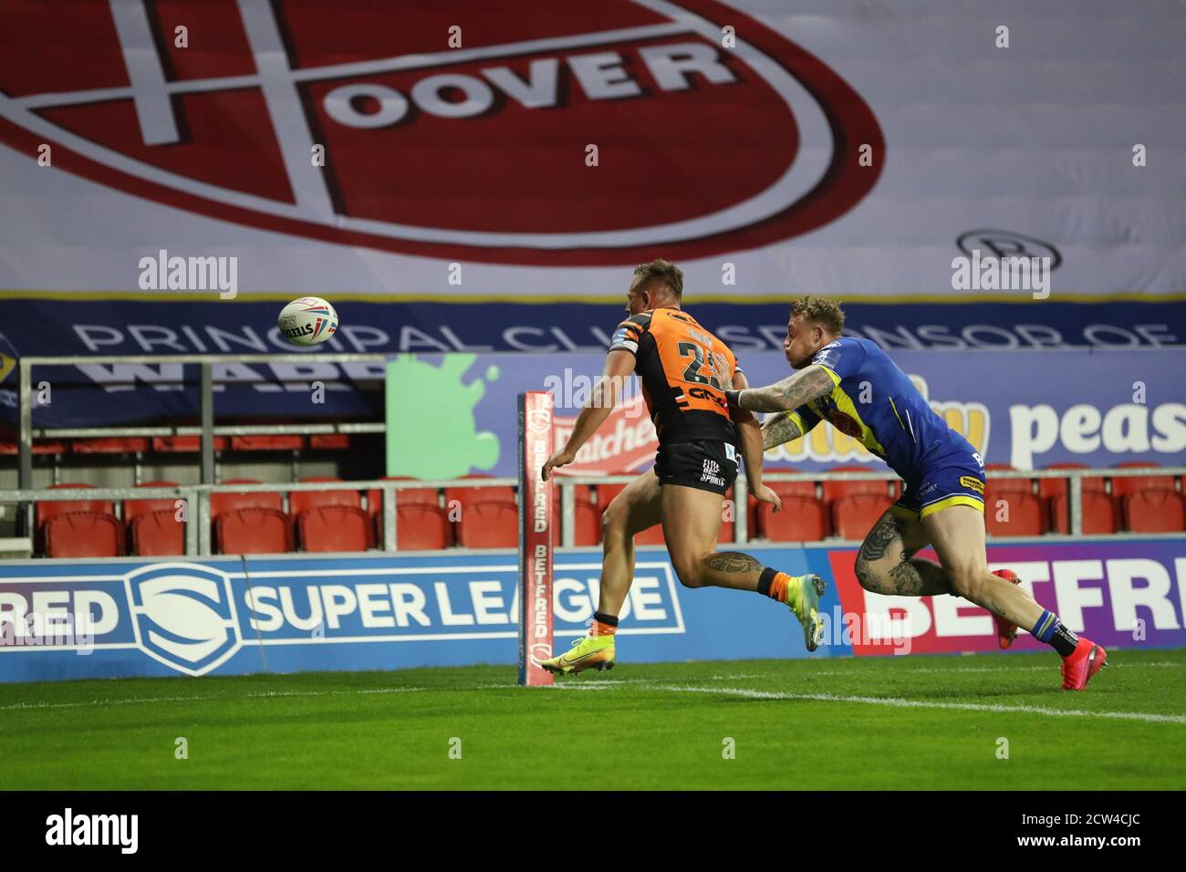 Greg Eden (25) di Castleford Tigers bussa alla palla Se giocare asJosh Charnley (5) di Warrington Wolves pressioni cercando per una prova Foto Stock