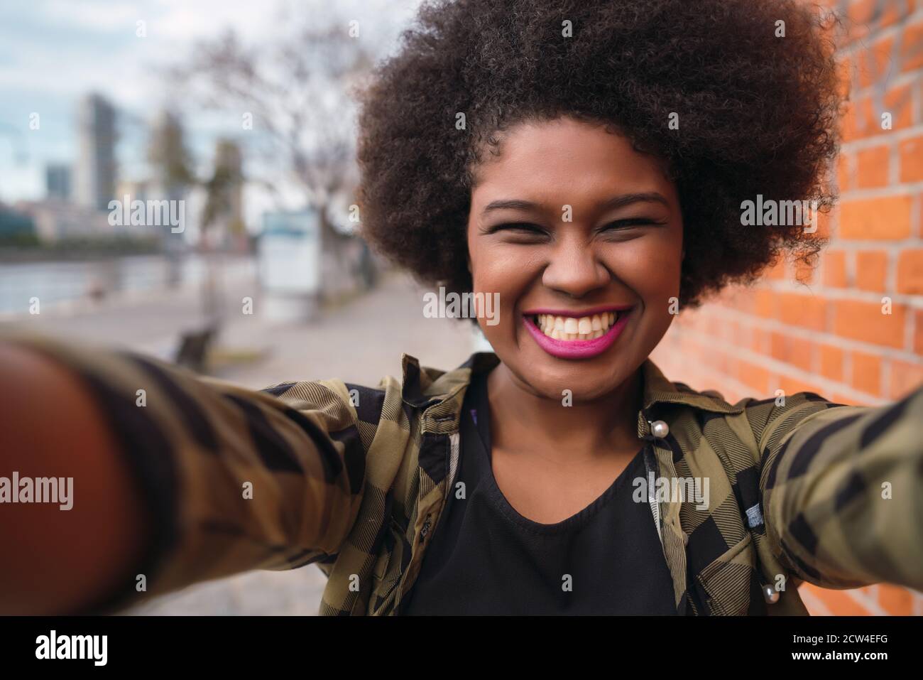 Ritratto di giovane bella donna afro americana prendendo un selfie all'aperto in strada. Foto Stock