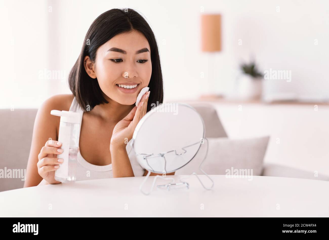 Giovane donna che pulisce il viso con un panno di cotone Foto Stock