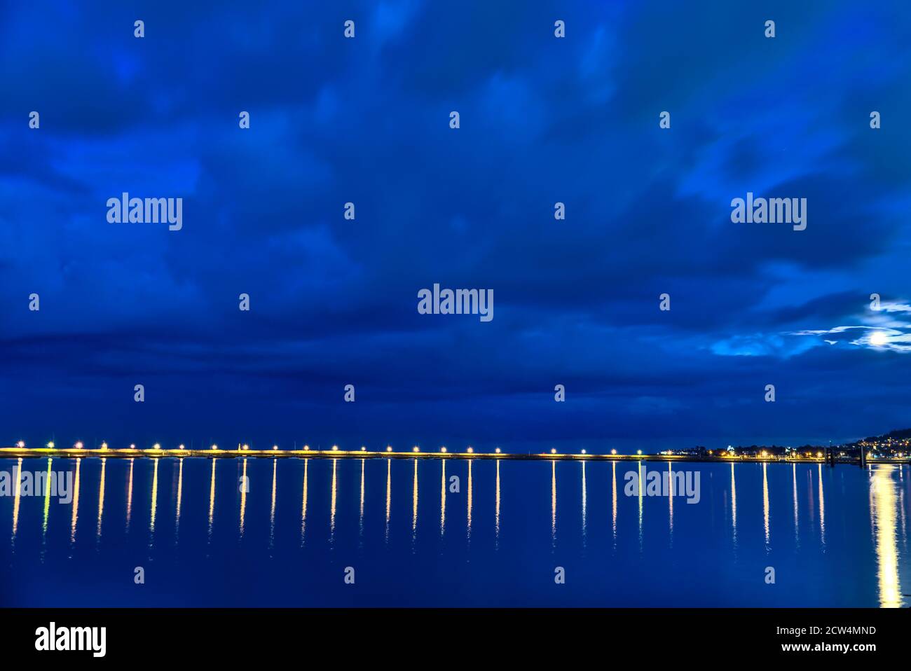 Bella lanterne del porto di illuminazione in serata. Riflessione della luce nell'acqua. Molo est del porto di Dun Laoghaire durante l'ora blu, Dublino Foto Stock
