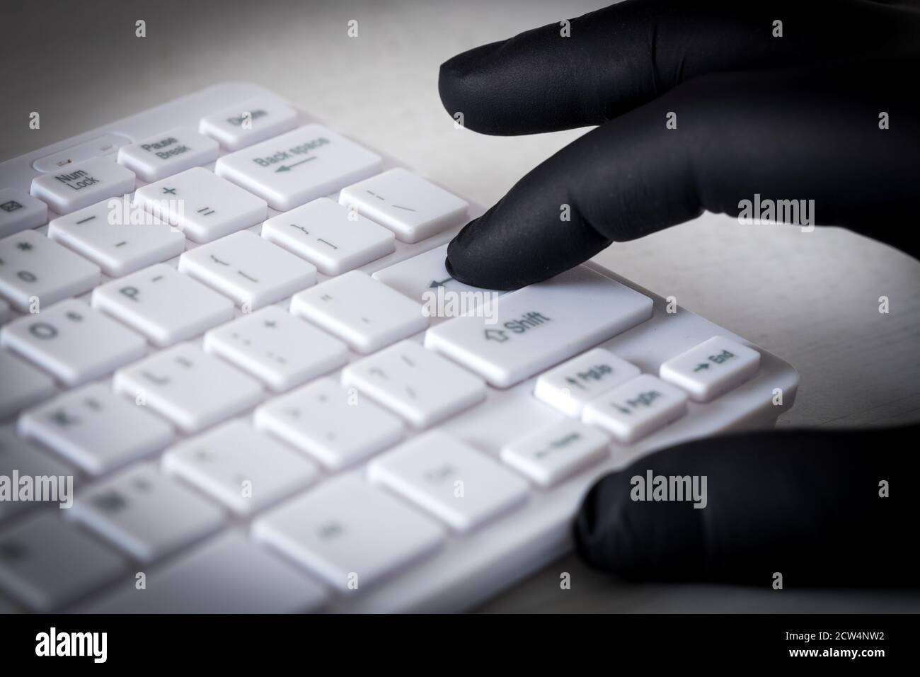 Tastiera e mani bianche del computer in guanti di gomma nera. Concetto di criminalità e molestie sul web Foto Stock