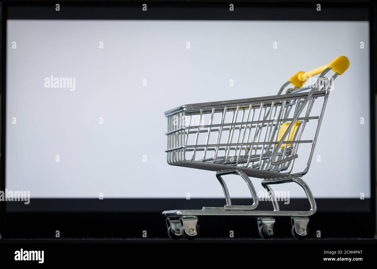 carrello della spesa sulla tastiera del computer portatile. Schermo del monitor bianco con spazio per il testo. Concetto di shopping online e negozi online Foto Stock