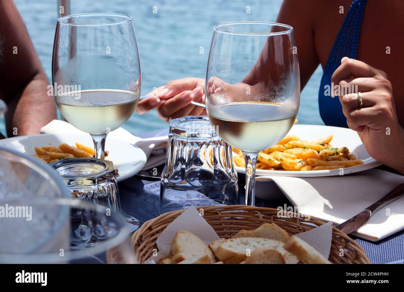 Vista ravvicinata di una coppia che pranza con la pasta italiana e. vino bianco vicino al mare Foto Stock