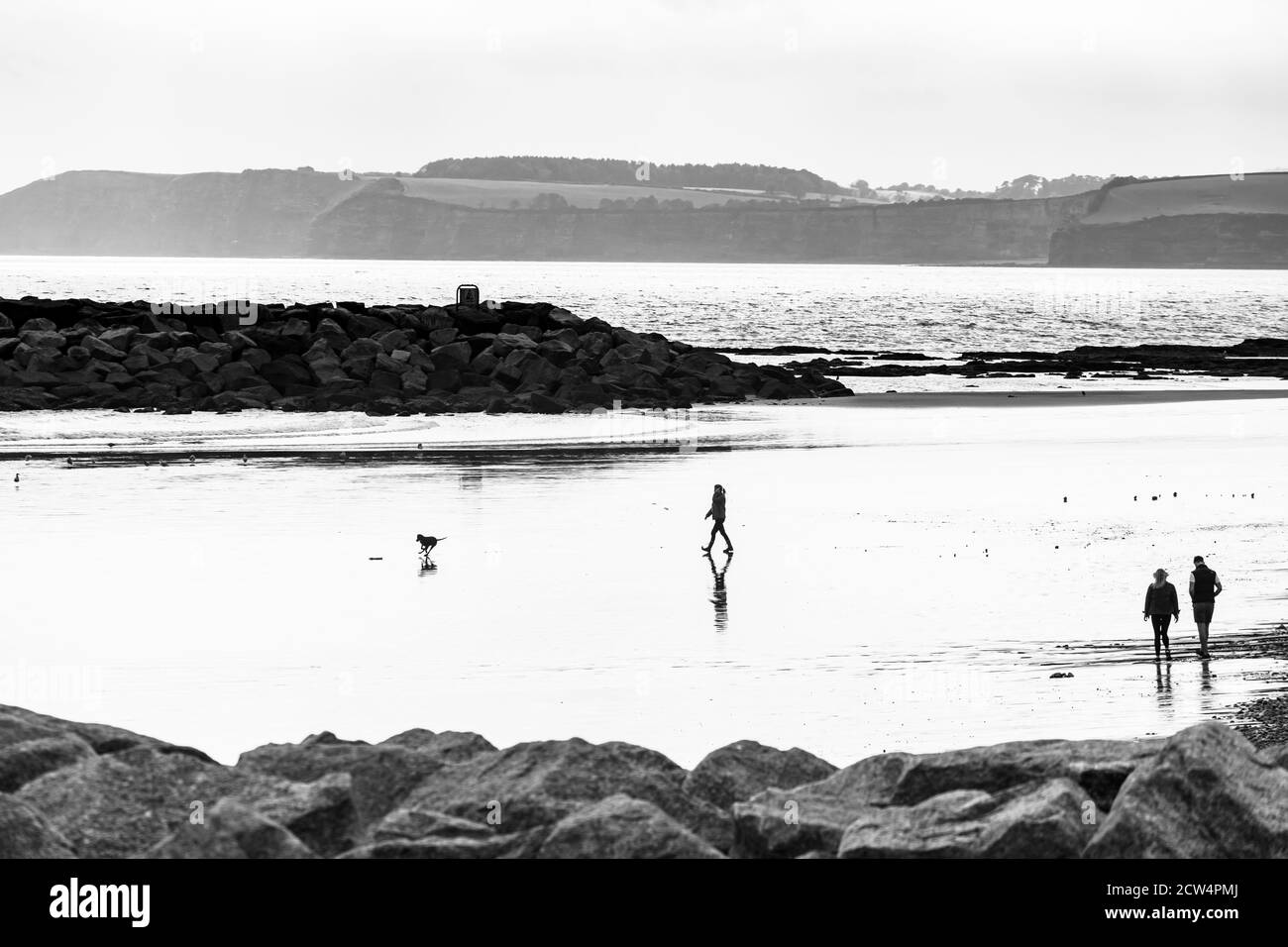 Alta immagine chiave degli escursionisti e delle loro riflessioni su Sidmouth Beach, Devon meridionale Foto Stock