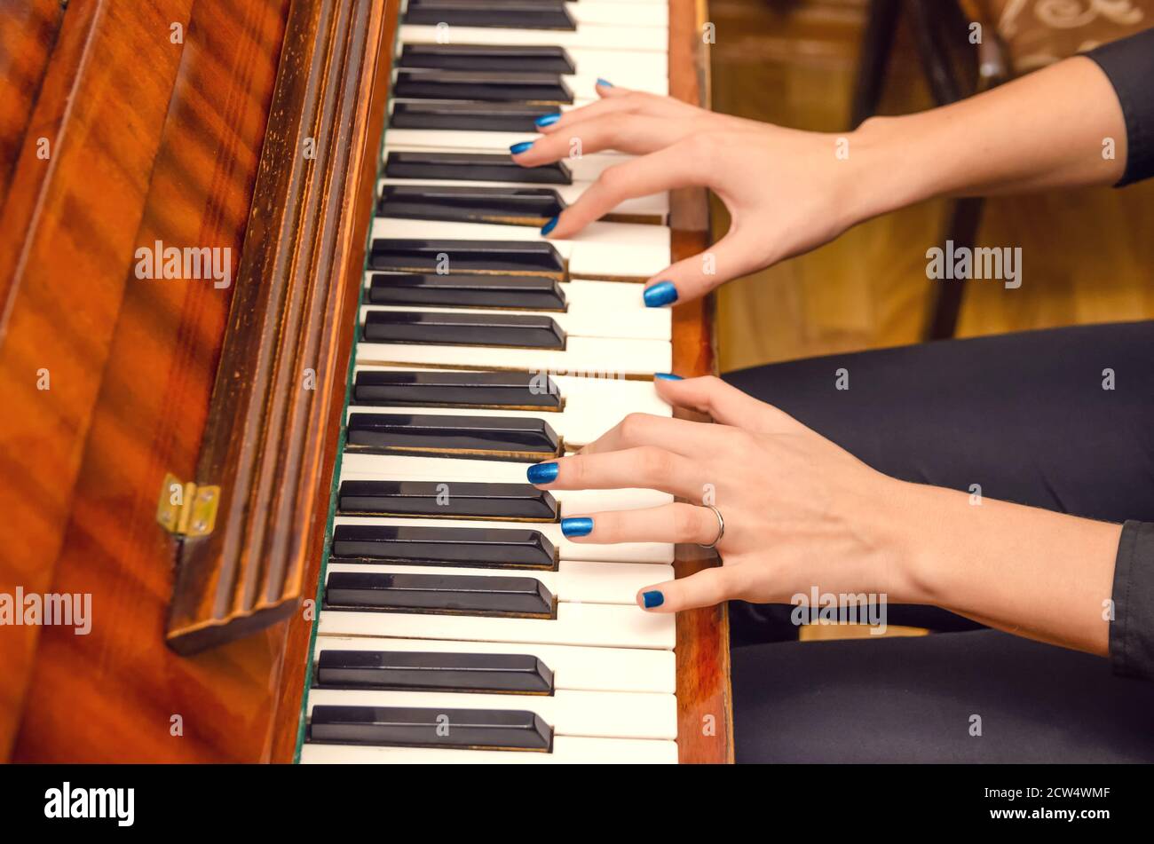 Mani di una pianista femminile con unghia blu polacca sui chiodi sulle chiavi di un pianoforte. Ragazza che suona il pianoforte. Foto Stock