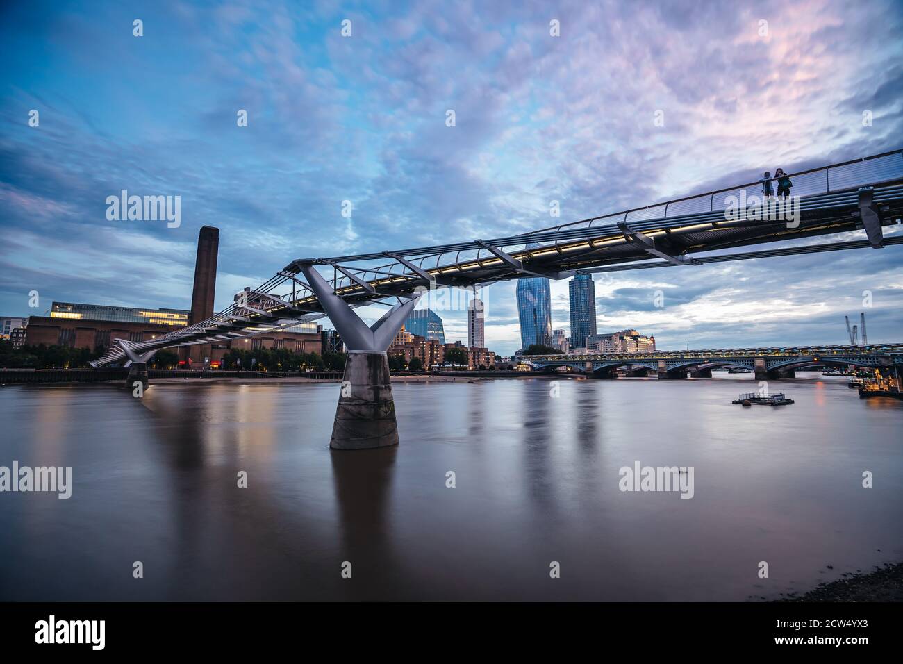 Londra / UK - 2020.07.18: Vista di Tate Modern e Tamigi dietro Millennium Bridge in un'evaping con il cielo nuvoloso blu ghiaccio Foto Stock