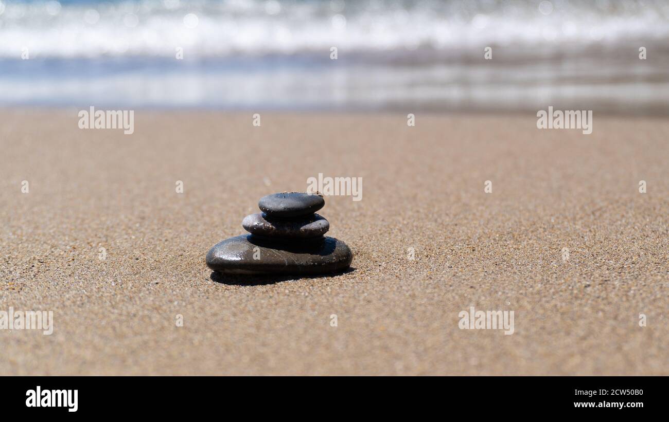 Meditazione in pietra sulla spiaggia di sabbia. Pietre equilibrate vicino al mare. Concetto di armonia, stabilità, equilibrio di vita, relax Foto Stock