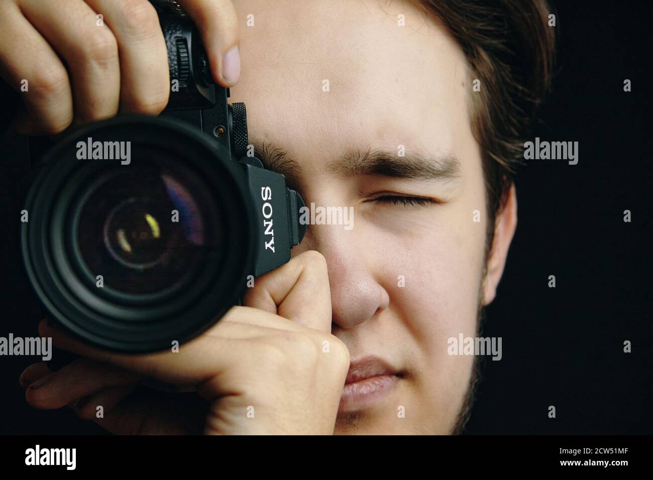 Man scatta foto con la fotocamera Alpha 7 di Sony. La persona cerca di mettere a fuoco l'obiettivo. Editor di foto, cameraman, giornalista. Bishkek, Kirghizistan - 15 dicembre 2019. Foto Stock