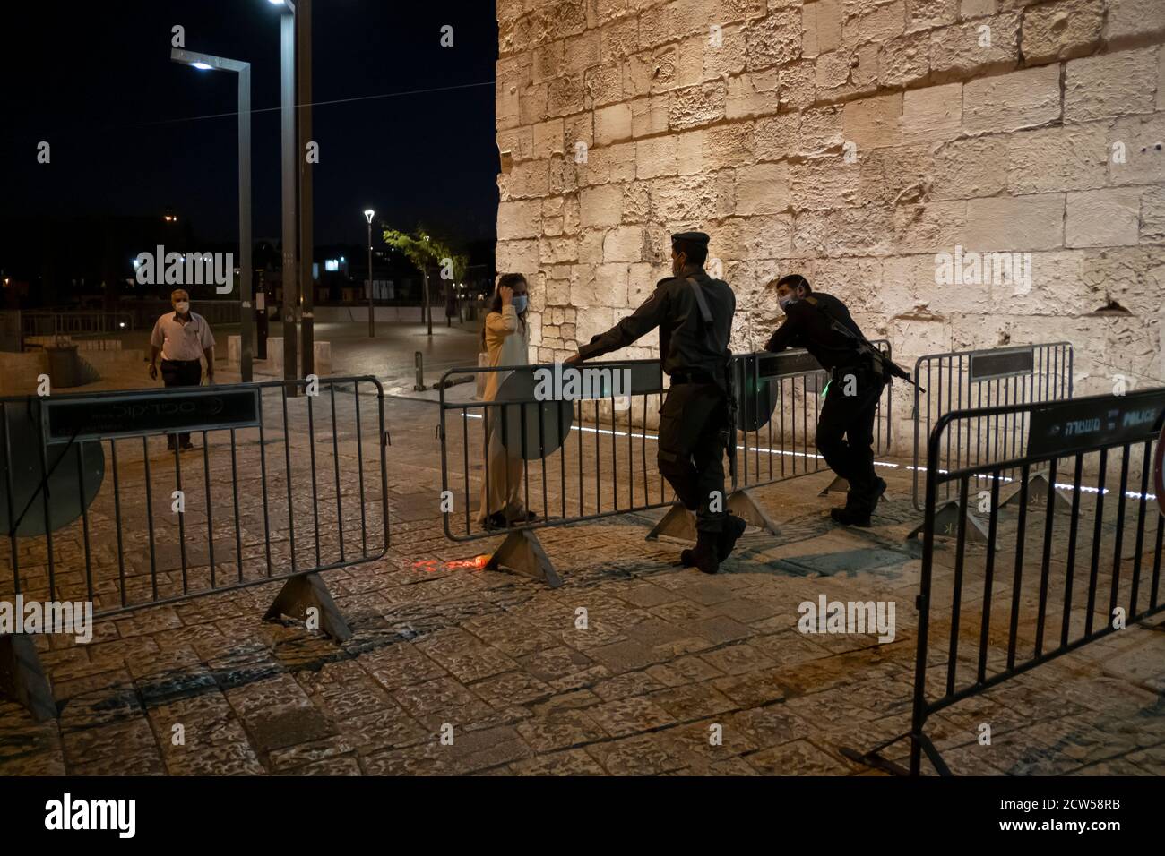 I poliziotti israeliani impediscono il passaggio di una donna in un checkpoint alla porta di Jaffa alla vigilia di Yom Kippur, mentre Israele entra in un nuovo blocco di Coronavirus il 27 settembre 2020 a Gerusalemme, Israele. La chiusura di tre settimane, che richiede la chiusura di molte imprese e la fissazione di limiti rigorosi sul movimento e le riunioni pubbliche, è iniziata poche ore prima di Rosh Hashana, il nuovo anno ebraico, e si estenderà attraverso altre importanti festività religiose. Foto Stock