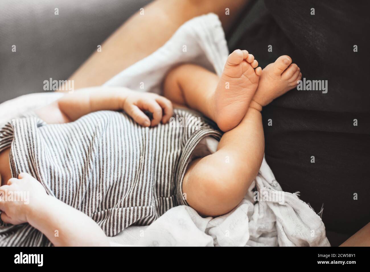 Primo piano foto dei piedi del bambino che giace su suo padre mentre provando a dormire in una giornata soleggiata Foto Stock
