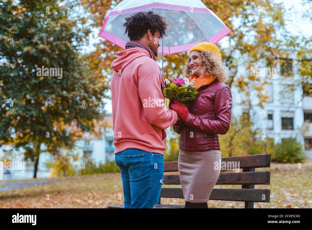 Uomo nero dando i fiori per la sua ragazza caucasica in autunno Foto Stock
