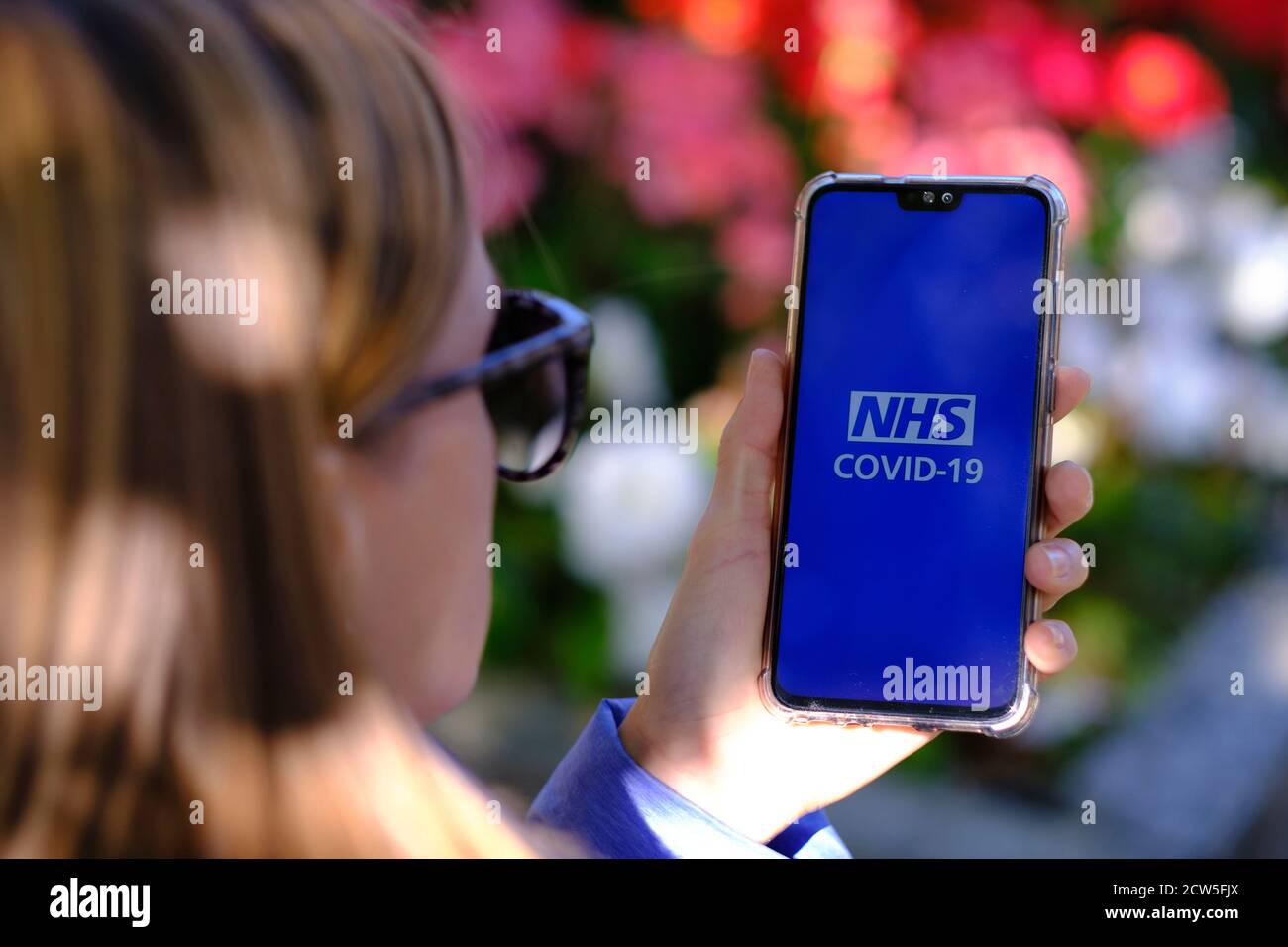 Stafford / UK - Settembre 27 2020: NHS COVID-19 app schermata di login visto sullo smartphone che la ragazza giovane senza maschera tenere in mano. Concetto di tra Foto Stock