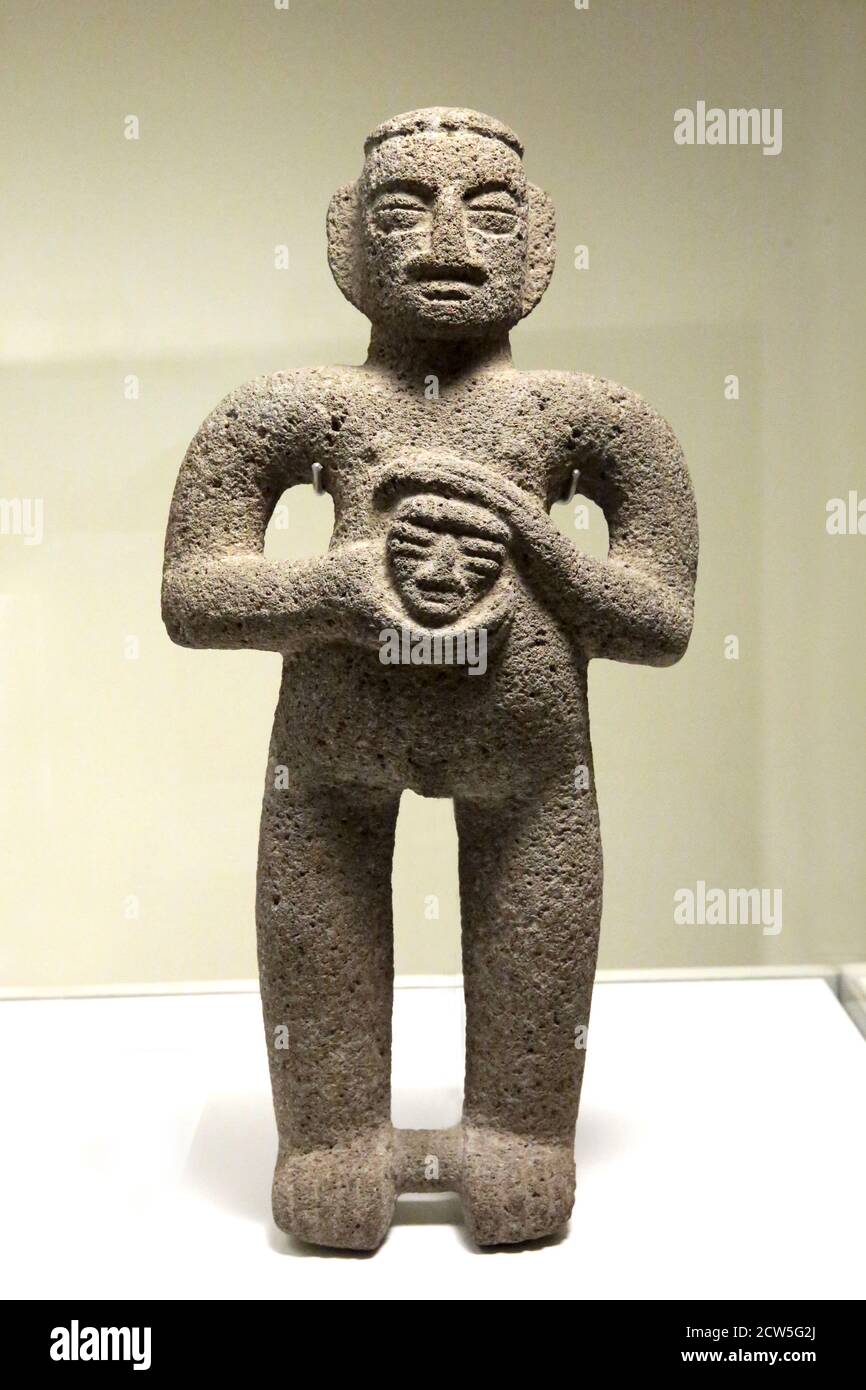 Personaggio maschile che tiene una testa trofeo. Scultura in pietra (1000-1500 d.C.). Precolombiano art. Costa Rica. Museumj delle culture del mondo, Barcellona, Spagna. Foto Stock