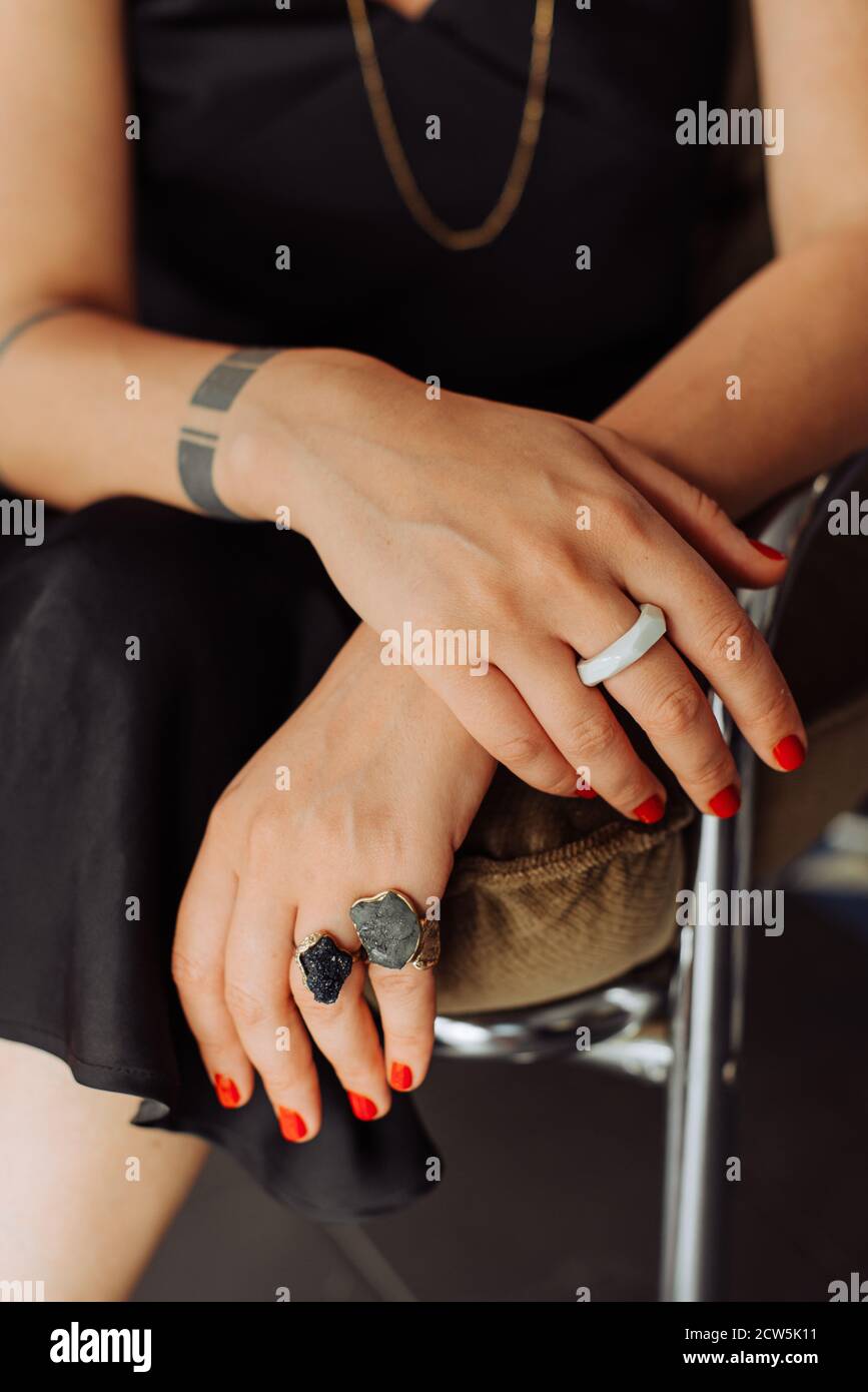 Primo piano delle mani femminili con smalto rosso per unghie e. anelli Foto Stock