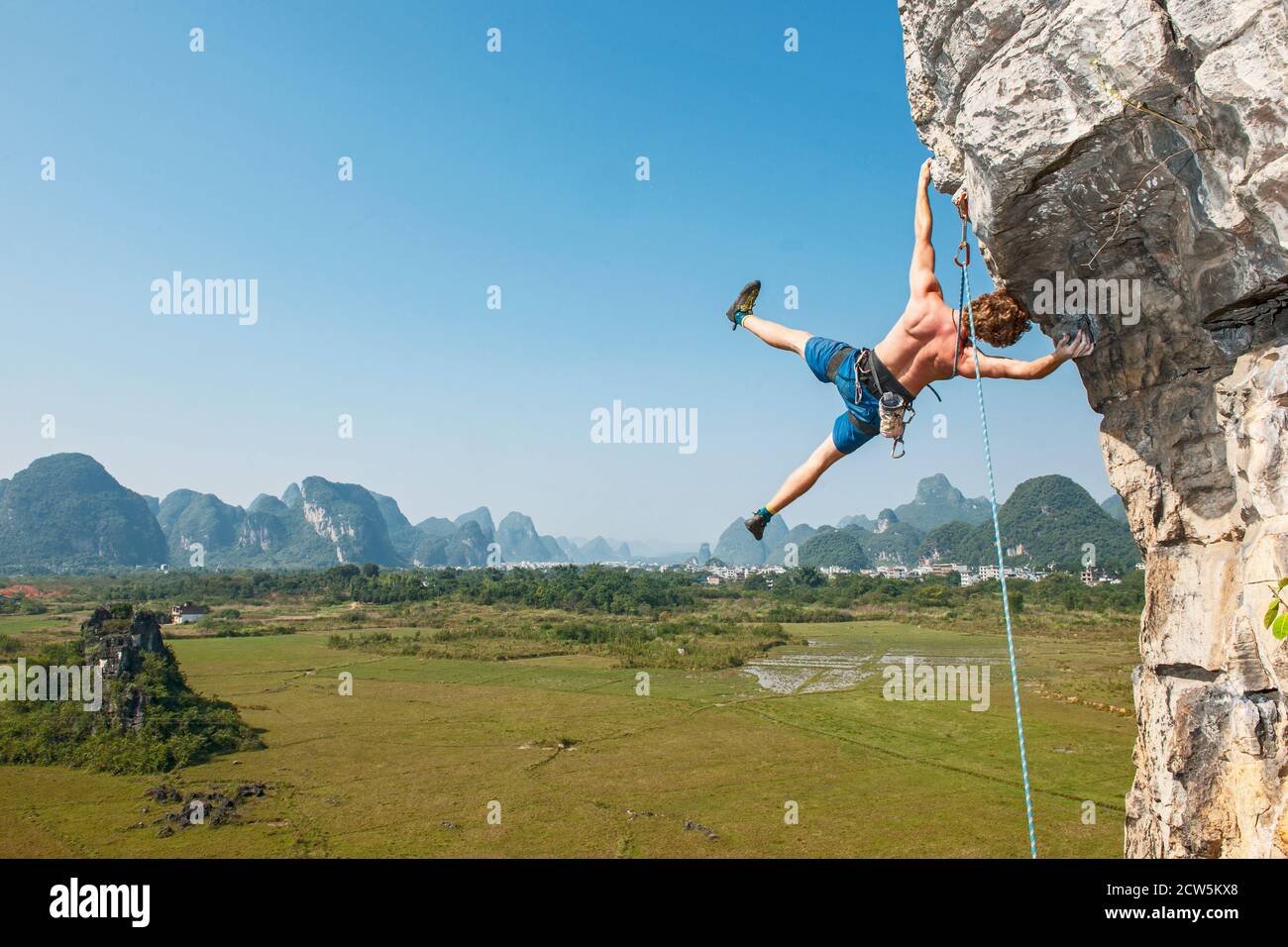 Arrampicatore maschio appeso lateralmente su roccia sospesa a Yangshuo / Cina Foto Stock