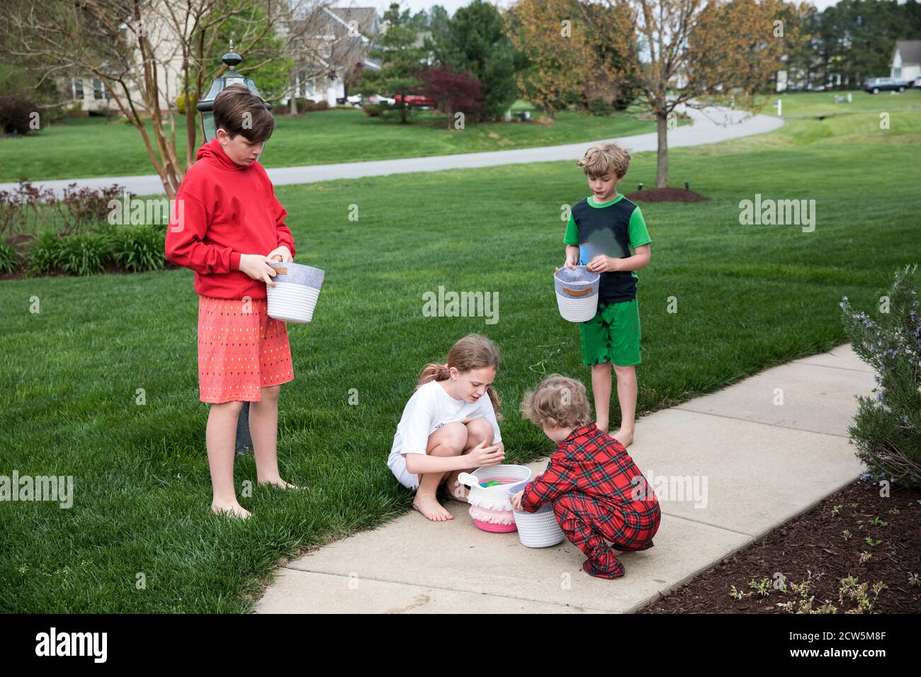 Quattro fratelli del PJS esaminano le uova di pasqua nei cesti di Front Yard Foto Stock