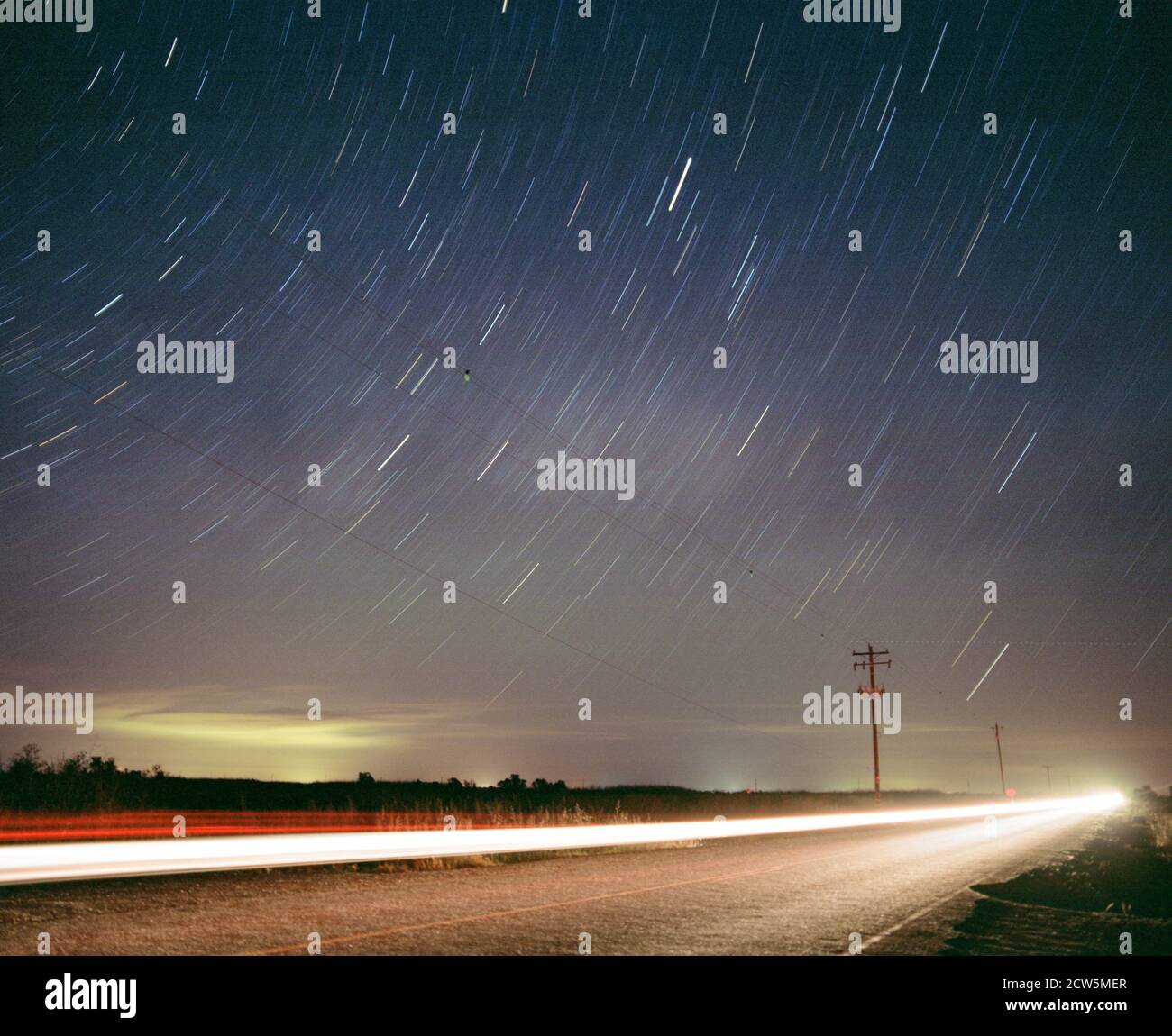 Star Trails sopra la strada con auto a lunga esposizione e telefono palo Foto Stock