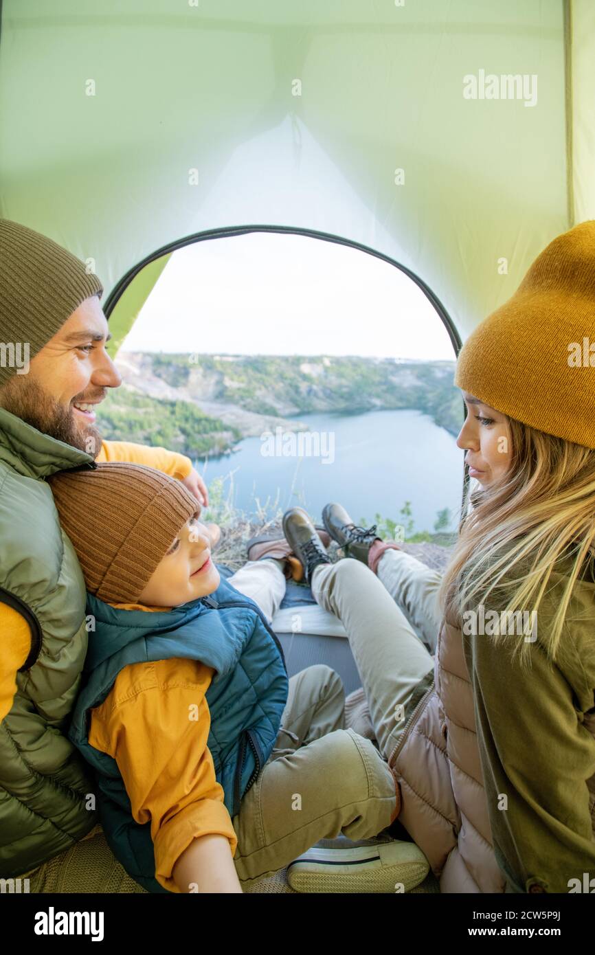 Giovane donna che parla con il bambino seduto da padre mentre la famiglia che riposa Foto Stock