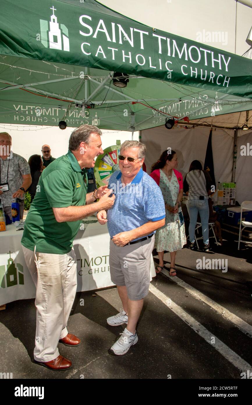 Un diacono cattolico socializza con i parrocchiani in una mostra di fuorilegge di una fiera di strada a Laguna Niguel, CA. Foto Stock