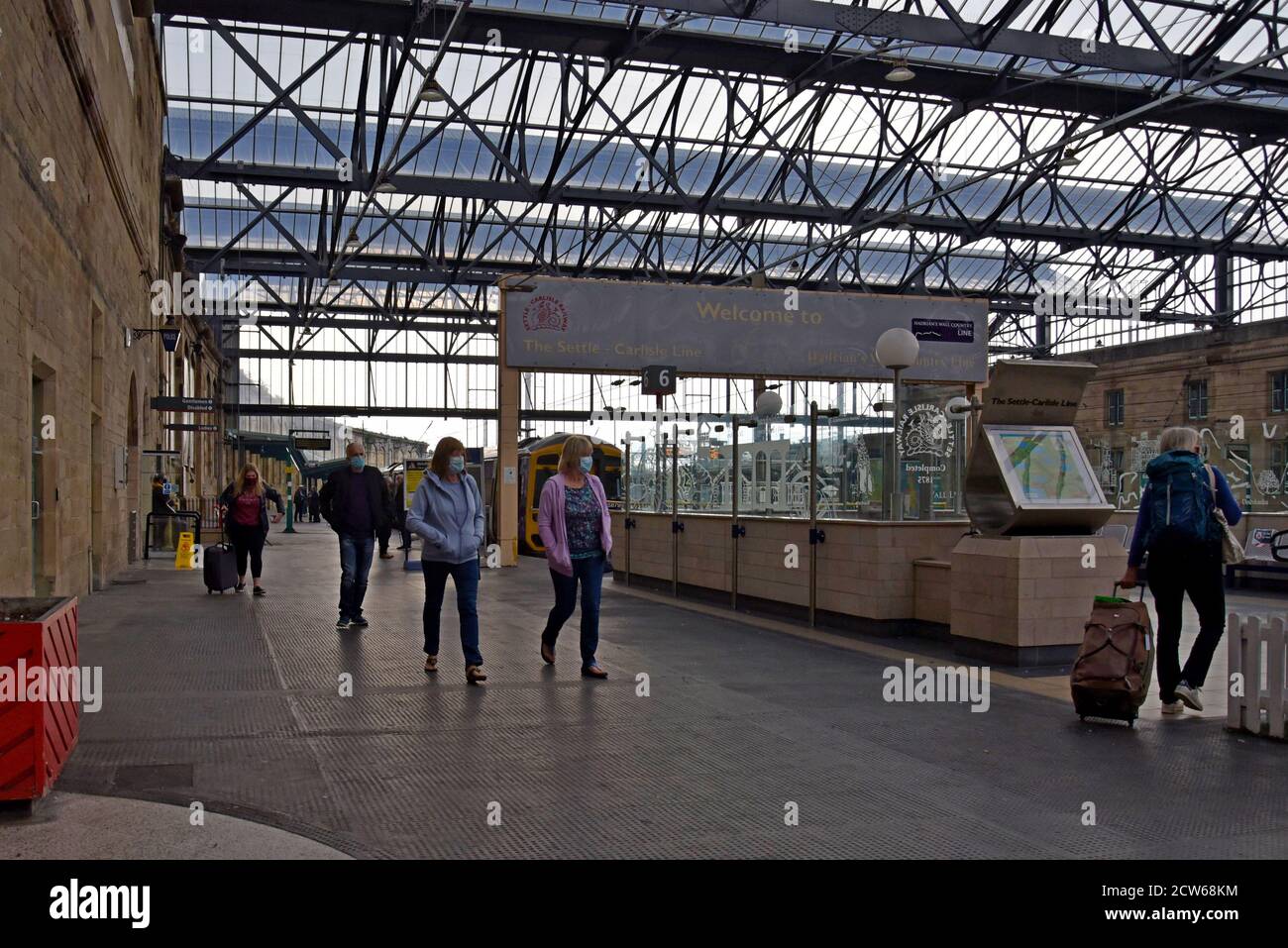 Passeggeri in maschere facciali che lasciano un treno dalla sistemazione E la linea Carlilse alla stazione di Carlisle Foto Stock