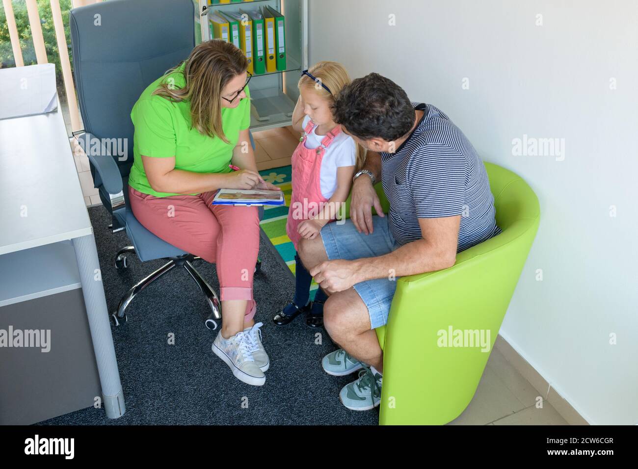 Padre e figlia preschooler in ufficio terapeuta durante la riunione di valutazione di consulenza. Assistente sociale che parla con singolo padre durante l'intervista. Foto Stock