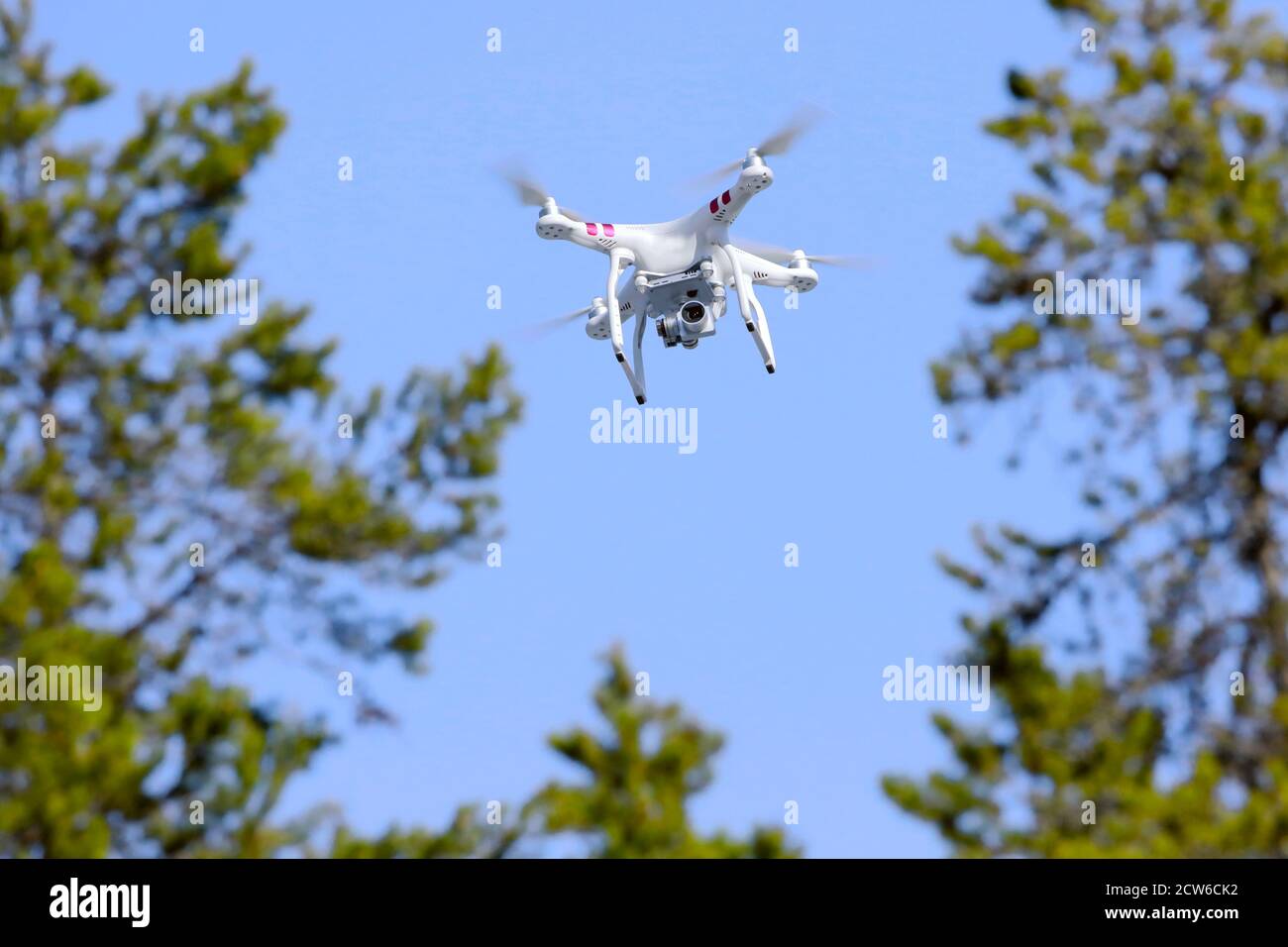 Quad-copter Drone con videocamera collegata in missione di ricerca e salvataggio, volando sopra le cime degli alberi. Foto Stock