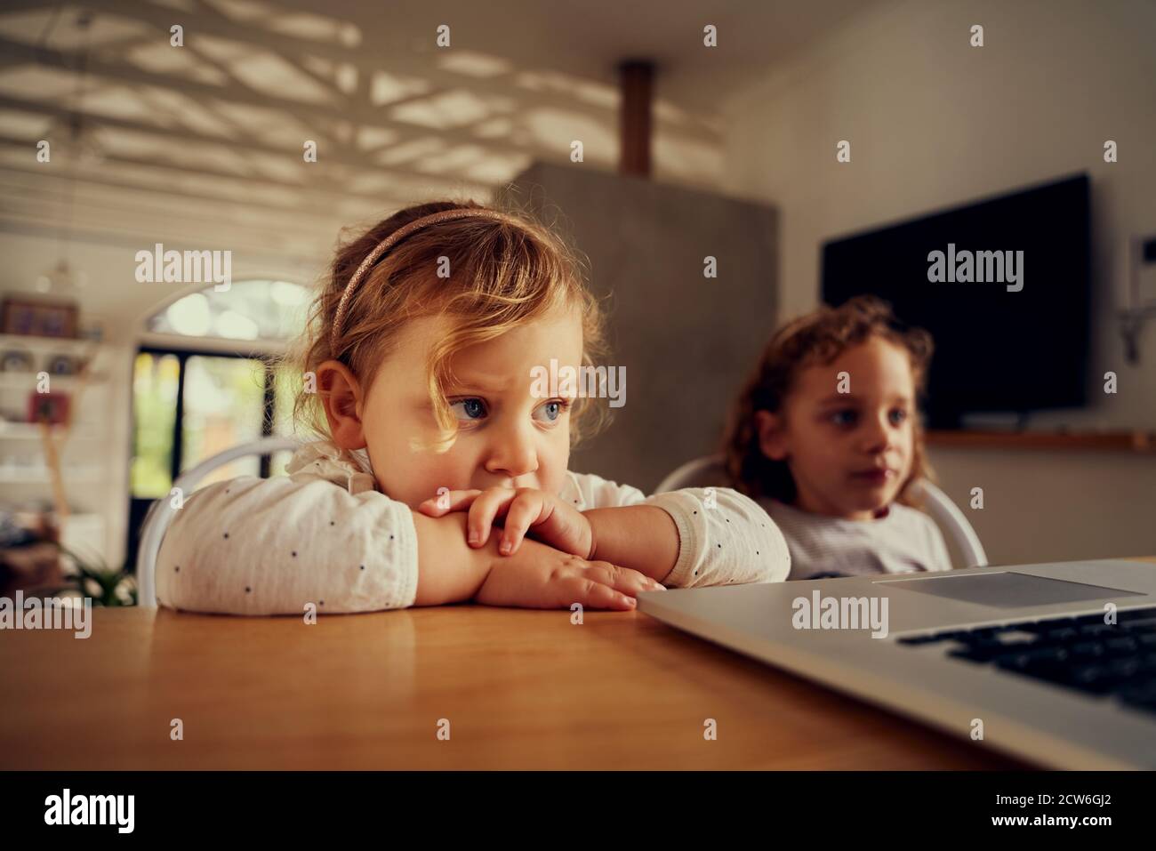 due giovani sorelle che guardano un computer portatile in una casa moderna - due ragazze che trasmettono in streaming su un notebook Foto Stock