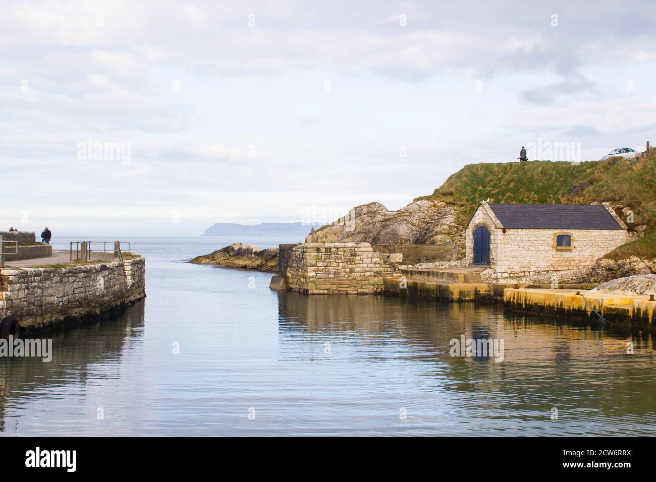 Il piccolo porto di Ballintoy sulla costa North Antrim dell Irlanda del Nord con la sua antica pietra costruito il boathouse in un giorno di primavera Foto Stock