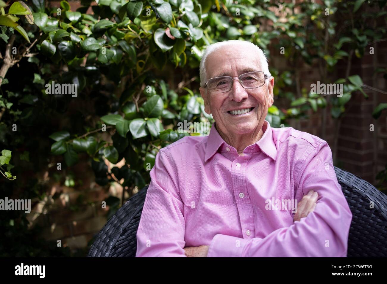 Ritratto di sorridente uomo anziano che si rilassa in giardino a casa Foto Stock