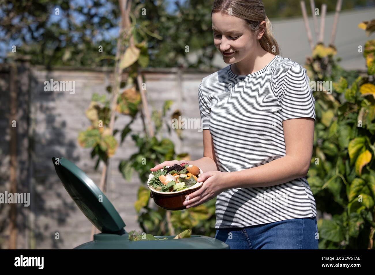 Donna che svuota rifiuti alimentari in Garden Composter a casa Foto Stock