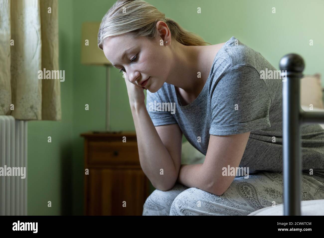 Donna infelice che soffre con depressione seduta sul letto che indossa Pajamas Foto Stock