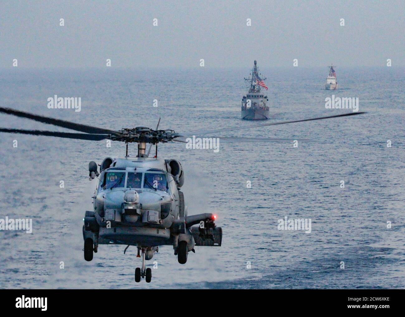 200924-N-PS962-0029 GOLFO PERSICO (SETTEMBRE 24, 2020) un elicottero MH-60R Sea Hawk, la nave di pattuglia costiera della Marina USS Tempest (PC 2), centro, E la nave di pattuglia della Guardia Costiera USCGC Adak (WPB 1333) si spostano in formazione durante l'operazione aerea congiunta a sostegno della guerra di superficie marittima (AOMSW) con il cacciatorpediniere missilistico guidato USS Winston S. Churchill (DDG 81), non raffigurato, nel Golfo Arabico, settembre 24. Winston S. Churchill viene dispiegato nella 5esima area di attività della flotta degli Stati Uniti a sostegno delle operazioni navali per garantire la stabilità e la sicurezza marittima nella Regione Centrale, collegando il Mediterraneo e la P. Foto Stock