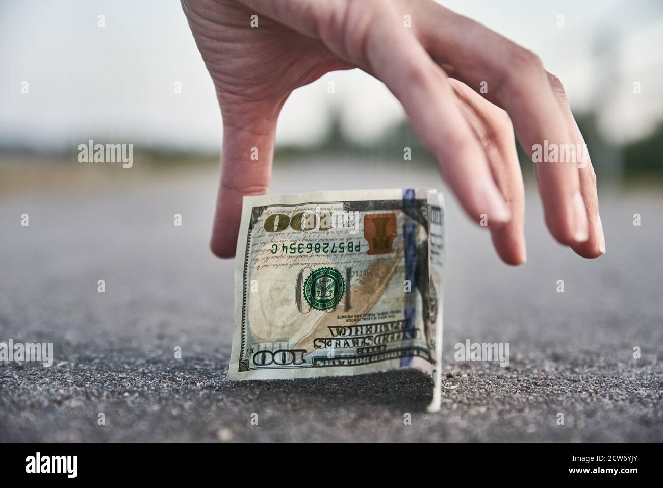 Prelevare a mano una banconota da cento dollari da terra. Trovato concetto di denaro Foto Stock