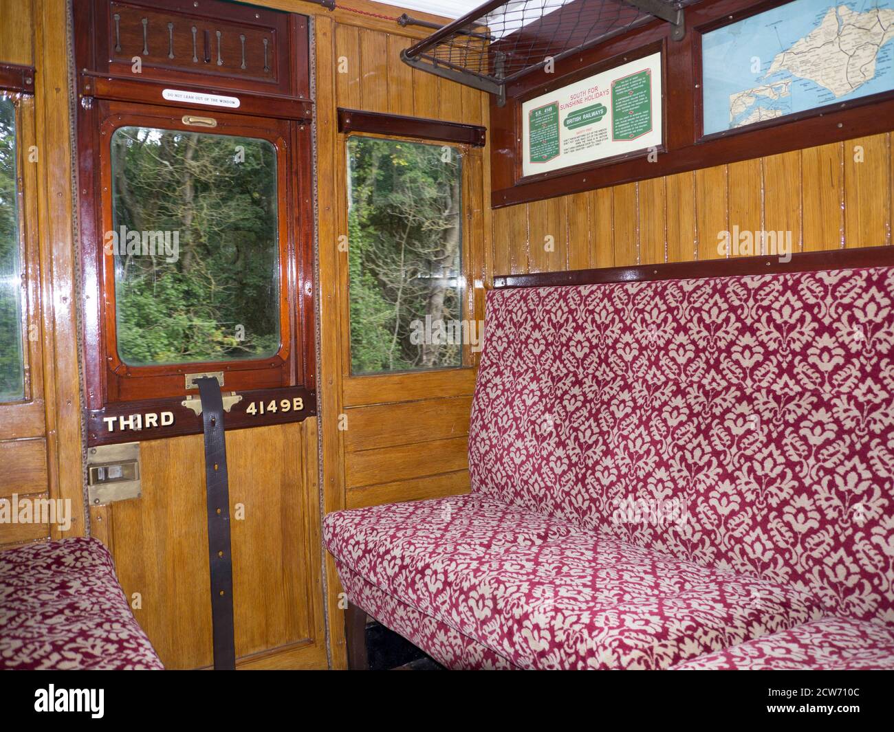 Interno storico carrozza ferroviaria con pannelli in legno lucido e finestra di apertura a discesa. La finestra è stata sollevata e abbassata con un cinturino in pelle. Foto Stock