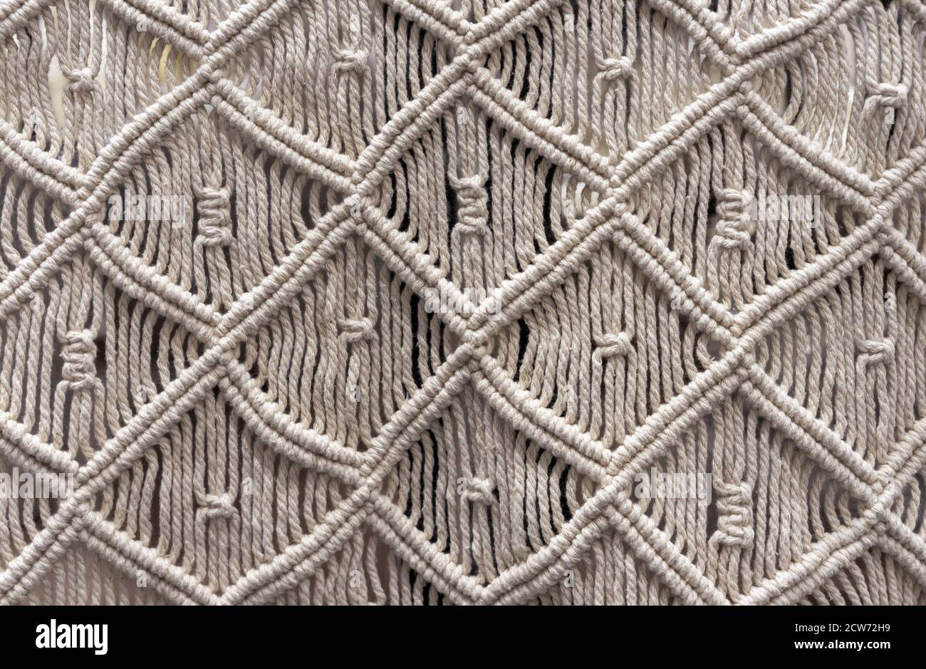 Macrame fatto di corda di lino beige. Tecnica di tessitura del nodo - macrame. Foto Stock