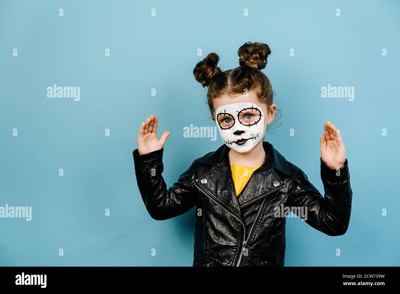 Cute piccola ragazza indossa spaventare trucco gesturing con le mani che mostrano grande e grande segno di dimensione, misura simbolo, isolato su sfondo blu studio. FAC Foto Stock