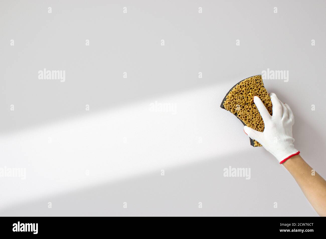 la mano tiene la spugna e lava un muro su uno sfondo bianco. Background del concetto di pulizia o pulizia Foto Stock