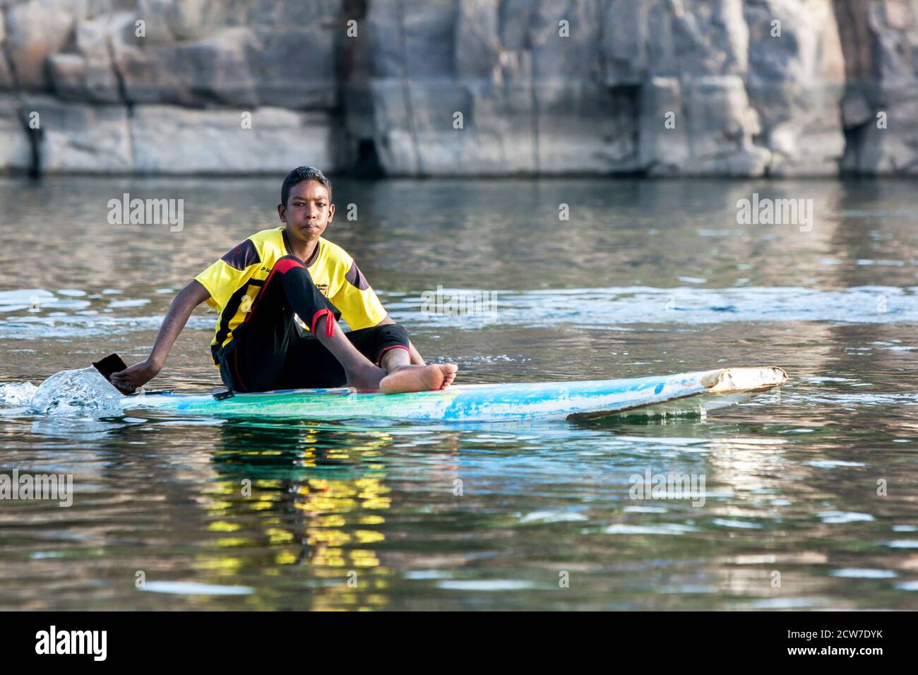 Un ragazzo egiziano pagaia una tavola da surf lungo il fiume Nilo ad Assuan nel sud dell'Egitto. Foto Stock