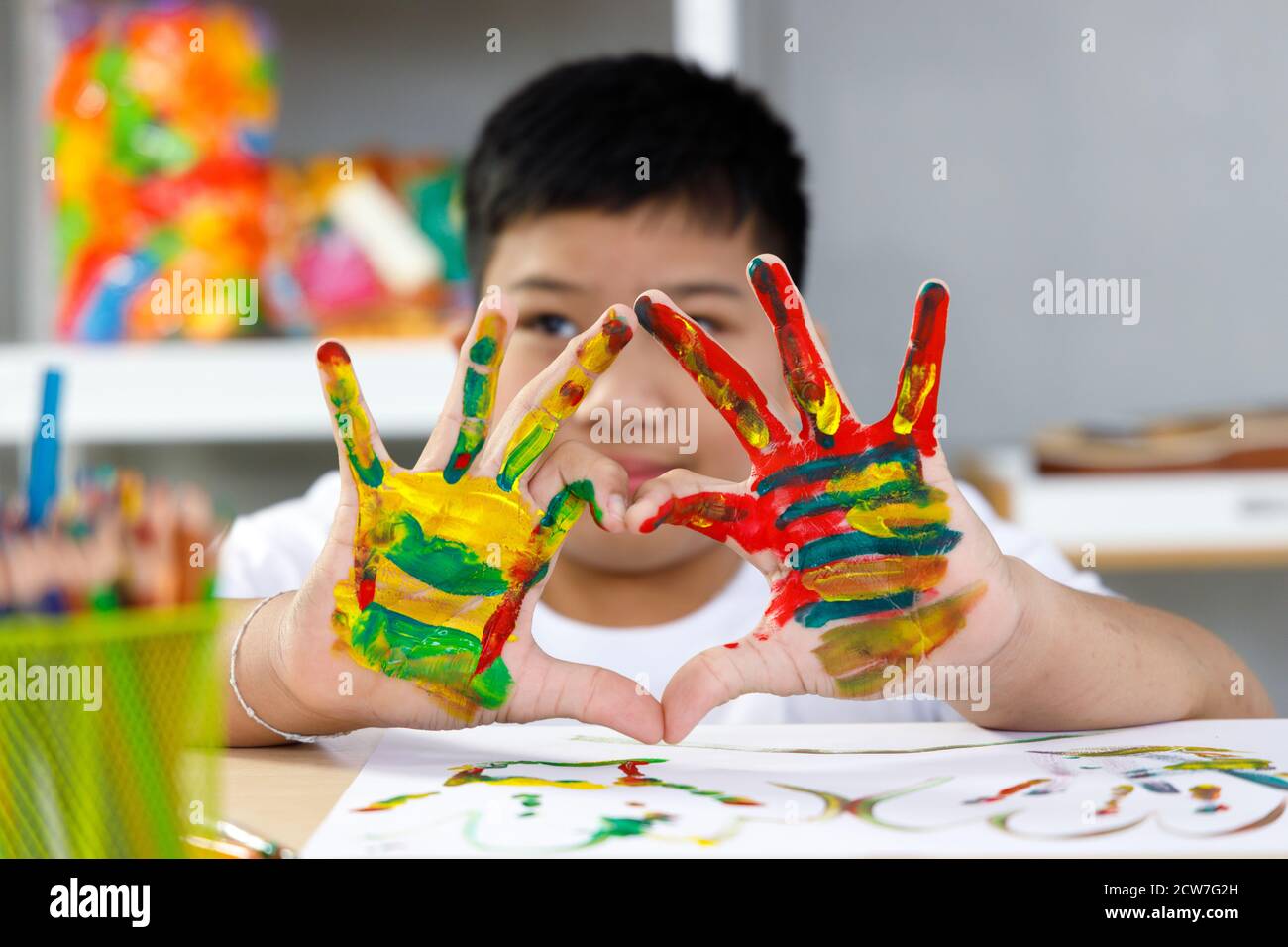 Ragazzo dipingeva la mano con giallo, rosso e verde in classe d'arte. Concetto bambini imparare a scuola. Foto Stock
