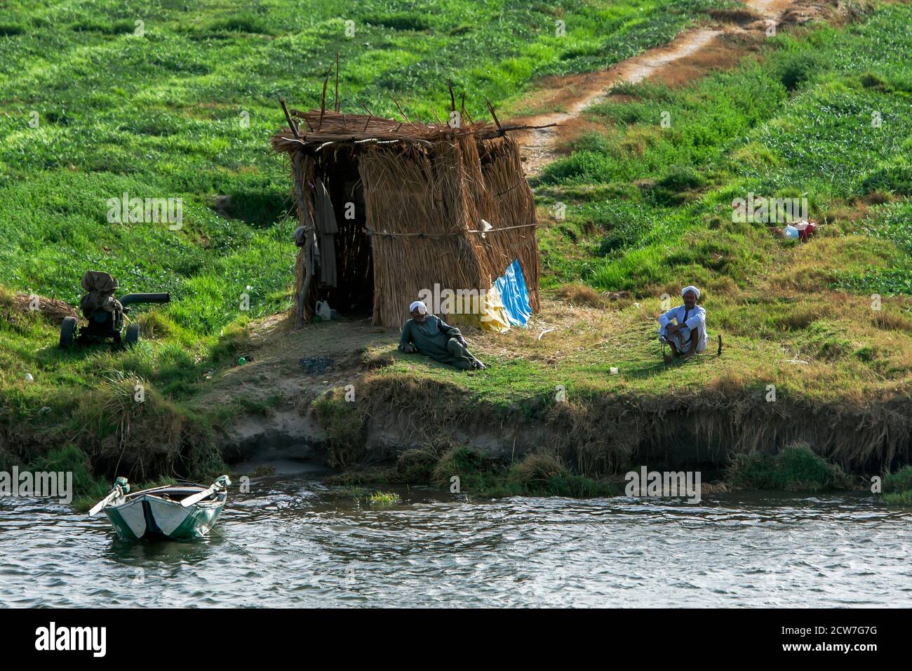 Gli uomini egiziani si rilassano sulla riva del Nilo nel tardo pomeriggio vicino alla serratura di Esna in Egitto. Le rive del Nilo hanno terreno ricco e sono irrigati Foto Stock